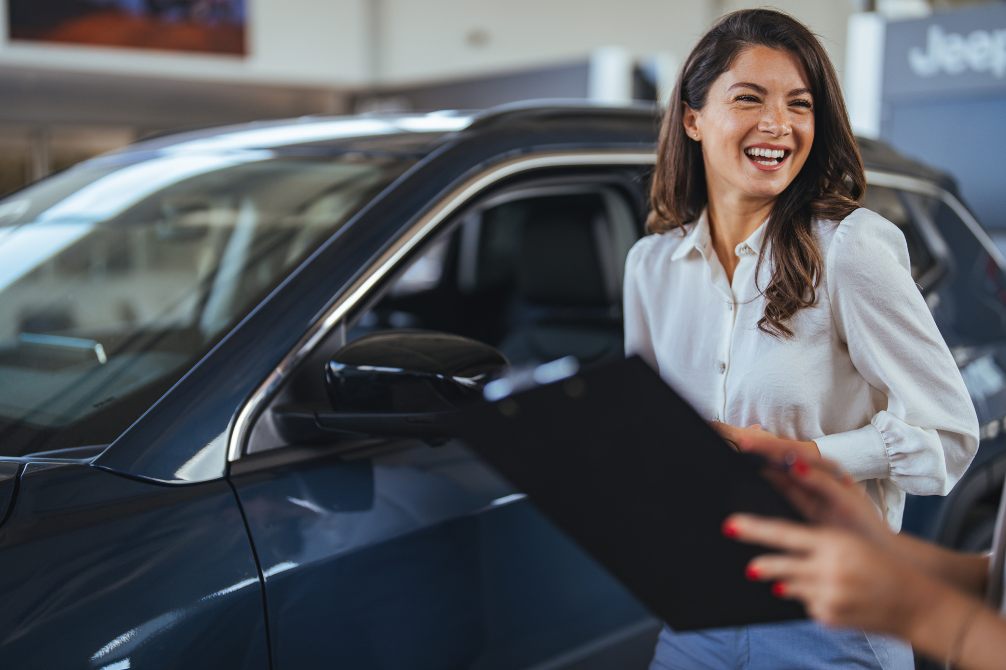 Woman looking happy beside a luxury car