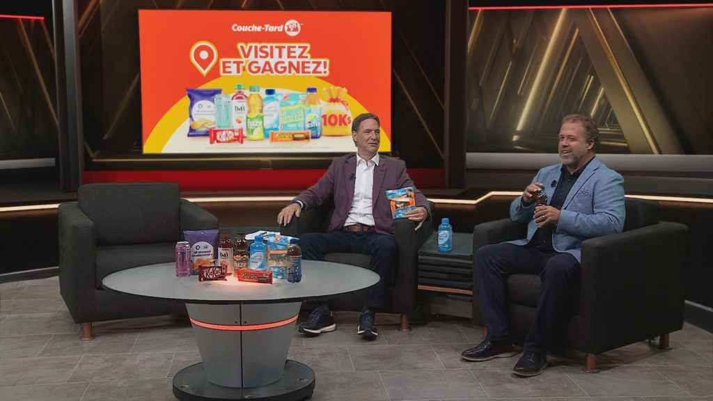 Plateau de l’émission L’Antichambre avec deux animateurs assis devant une table présentant des produits Couche-Tard, avec une promotion « Visitez et gagnez » affichée à l’écran.